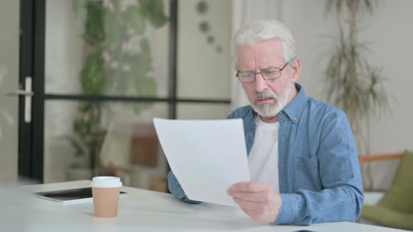 Senior Old Man Reacting to Loss While Reading Documents in Office