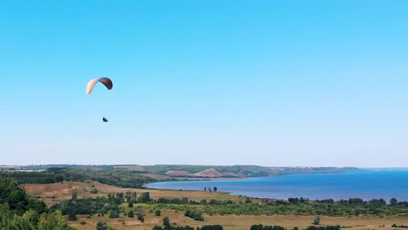 People Are Flying Over the Land and Water on the Paraplane. Man Paragliding. Beautiful Nature