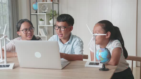 Young Asian Children Work As A Team Using Laptop Computers To Program Wind Turbines