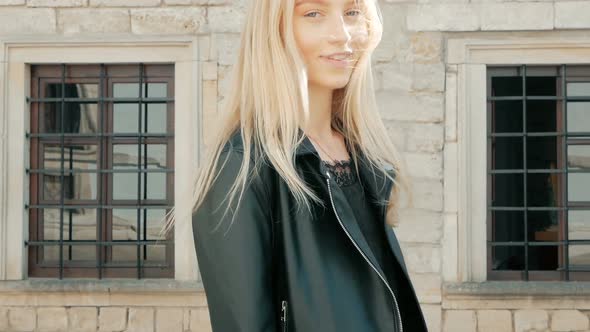 fashion portrait of a beautiful young woman with blue eyes and blonde hair in a leather jacket outdo