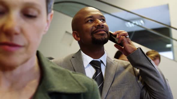 Businessman talking on mobile phone while standing in a line