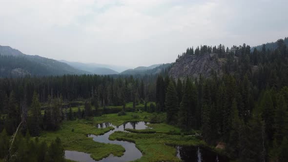 Crane drone shot of the Payette River in a forest in the Idaho wilderness. This stunning, smoky 4K c