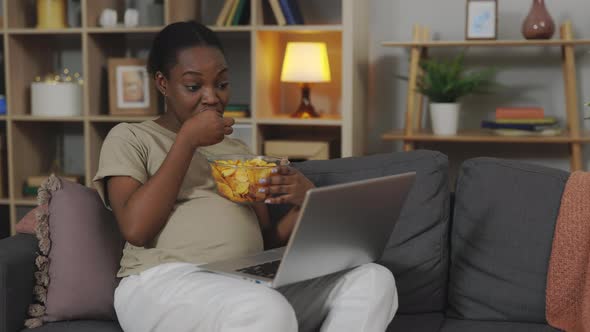 Future Mother Watching Movie and Eating Chips Indoors