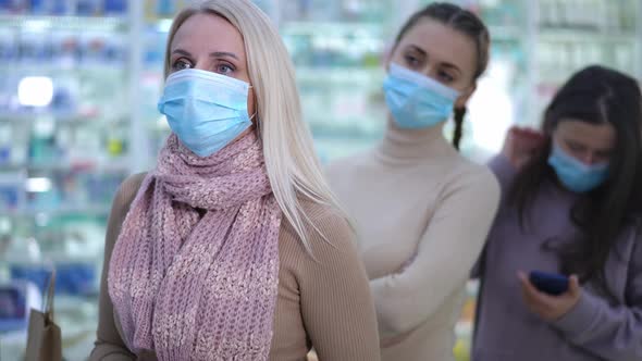 Caucasian Woman in Covid19 Face Mask Talking with Druggist in Pharmacy Buying Remedies with Blurred