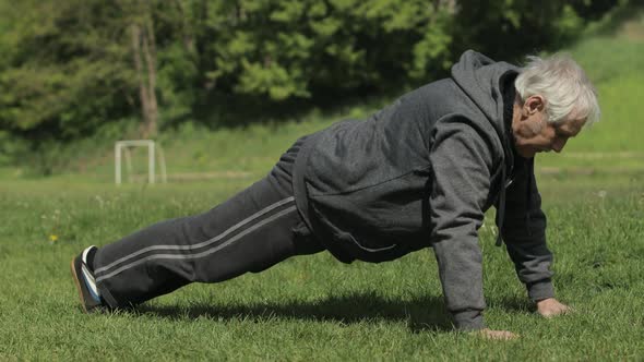 Active Senior Old Man Do Push-ups Physical Exercises in Sport Playground