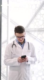 Male Doctor with Stetoscope Using Cellphone at Office