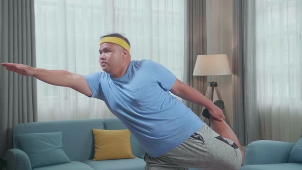 Fat Asian Man Trying To Do Yoga In Law Lord Of The Dance Pose On Mat At Home