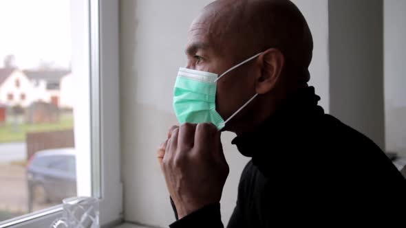 man with face mask looking out of his window being afraid of coronavirus disease stock video