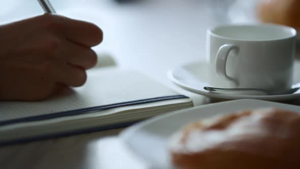 Woman Hand Writing Notepad Sitting Cafe Working Paperwork Notes in Restaurant