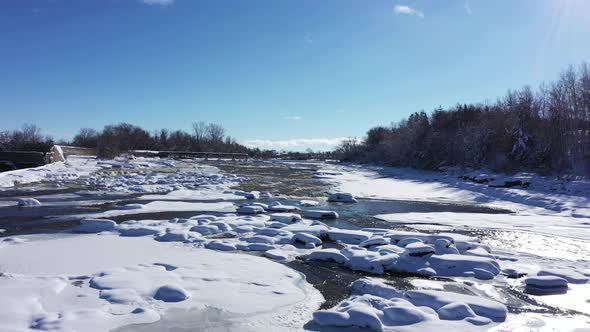 winter river system is half frozen on beautiful sunny day with fresh snow low flight