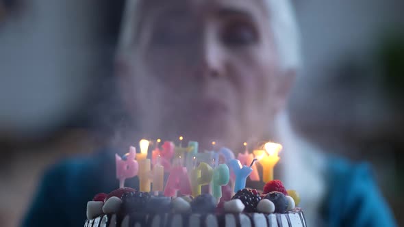 Happy Old Lady Blowing Candles on Birthday Cake