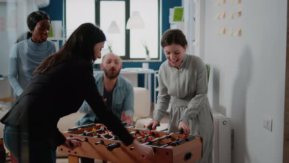 Colleagues Playing Foosball Game and Woman Winning