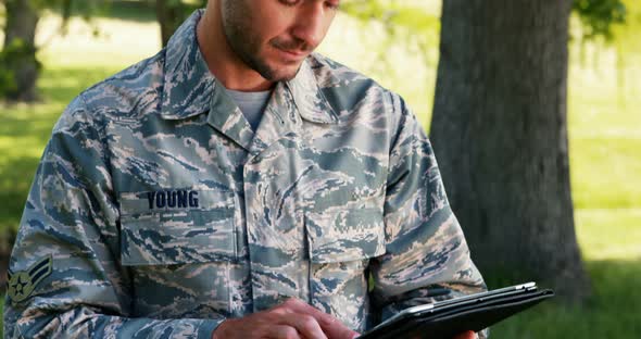 Soldier using digital tablet in park