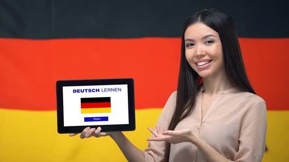 Lady Holding Tablet With Learn German App, Germany Flag on Background, Education