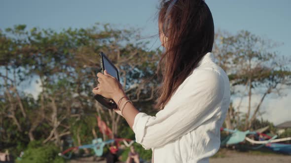 Woman with Tablet Walking on Beach