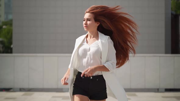 Woman runs along city street. Pretty playful lady is running in casual clothes.