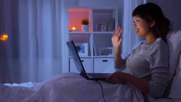 Woman with Laptop Has Video Call in Bed at Night