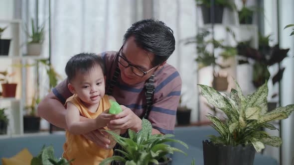 Happy Asian Man With Son Watering Plants At Home