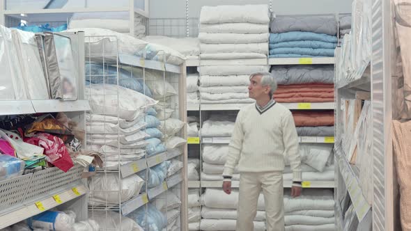 Elderly Male Customer Choosing Bedding at Home Goods Store