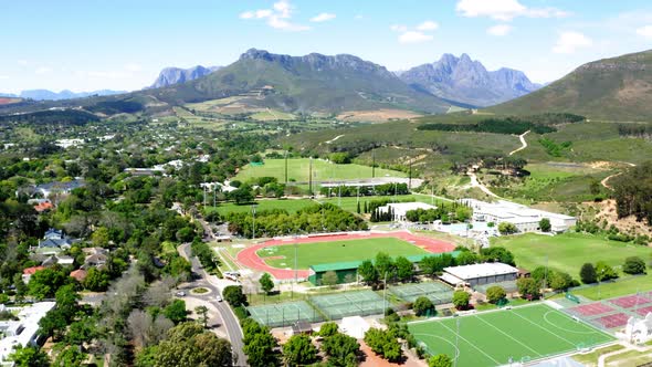 Aerial drone rotating, university college sports athletics stadium, track and field, tennis courts,