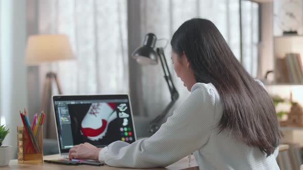 Asian Female Footwear Designer 3D Model Of Shoe And Change Colours While Working On A Laptop