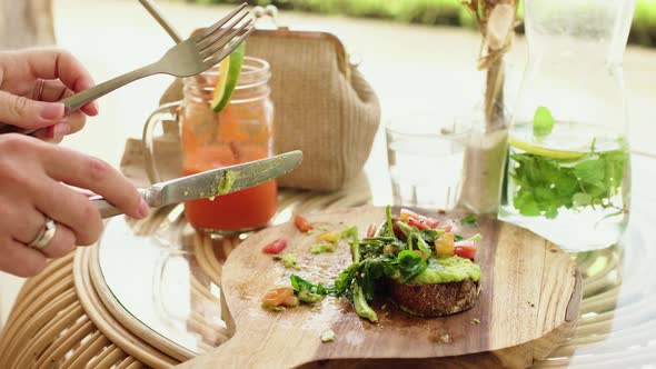 Woman having lunch cut green healthy sandwich in cafe