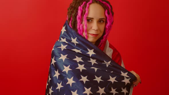 Young Woman Wrapped Up in American Flag on Red Background