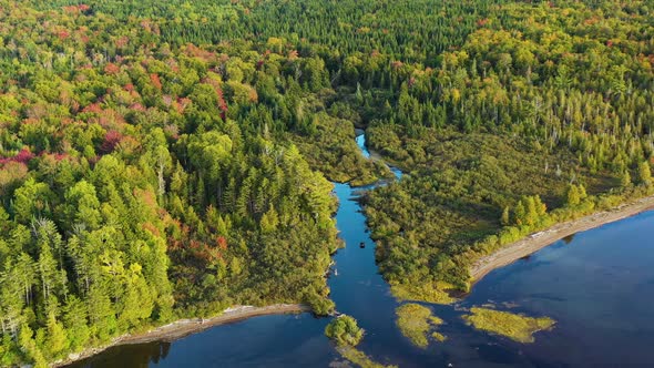 Aerial drone shot pushing in to a colorful blue mountain stream surrounded by autumn color leaves as