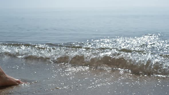 Tanned Woman Legs Splashing Ocean Waves on Sunlight Close Up