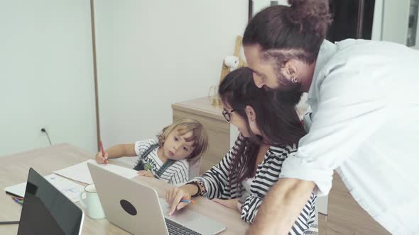 Mother, daughter and father using laptop at table