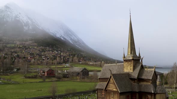 Lom Medieval Stave Church With Roof Detail Viking Symbol Against Misty Snow Mountains In Norway. Aer