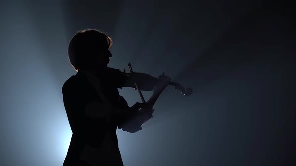 Violinist Plays a Lyrical Work. Black Smoke Background. Close Up. Silhouette