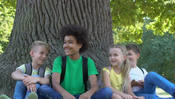 Cheerful Group of Children Joking Laughing Together Sitting Park Under Tree