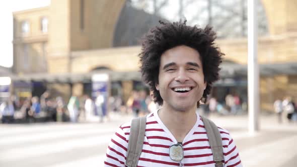 Man laughing in slow motion in front of busy train station