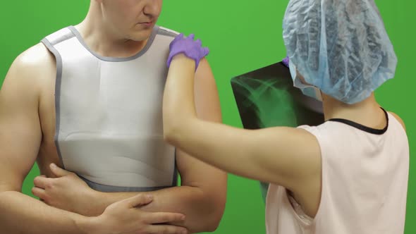 Man with Shoulder Injury. Nurse Examines X-ray. Bandage for Fixing Shoulder
