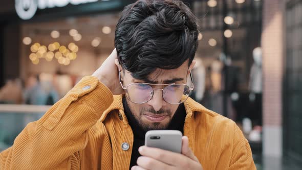 Closeup Sad Upset Shocked Young Indian Man Receiving Email on Smartphone Bankruptcy Notice Feels