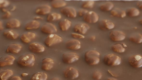 Close-up of milk chocolate with whole hazel nuts slow tilt 4K 2160p 30fps UltraHD footage - Fine tex