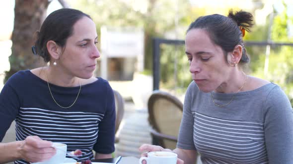 Two Caucasian female identical twins sitting together at a cafe