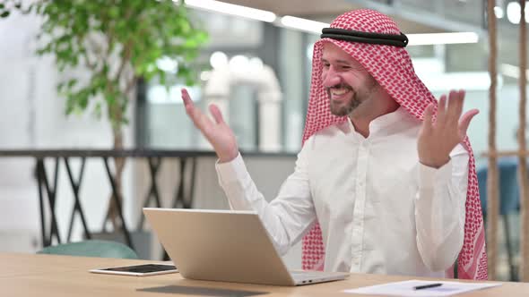 Excited Arab Businessman Celebrating Success on Laptop 