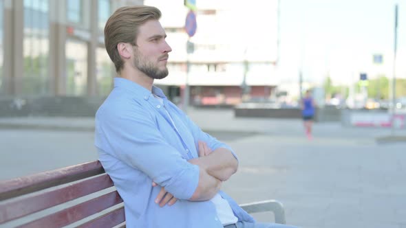 Young Man Looking at Camera While Sitting on Bench