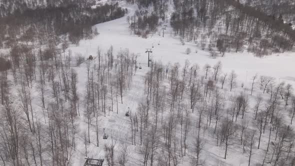 Flying over rope-way with gondolas at mountain resort Crystal Park in Bakuriani. Snowy winter day.