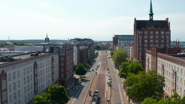 Forwards Fly Above Wide Street Lined with Massive Buildings