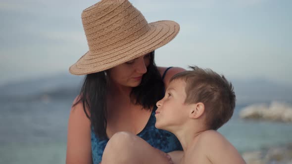 Mom and Son Sitting on the Beach By the Sea