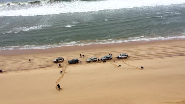 reveal shot of cars on the beach next to a huge dune in the Namib desert