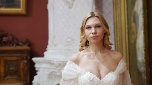 Beautiful Bride with Styled Hair Walks Through the Museum and Looks in the Camera