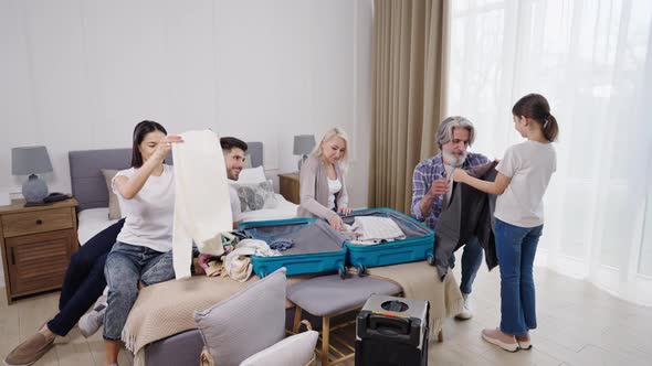 Family Helping Grandfather to Pack Clothes Into Suitcase Before Plane Flight