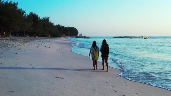 Modern smiling girls relaxing spending quality time at the beach on clean white sand and blue backgr