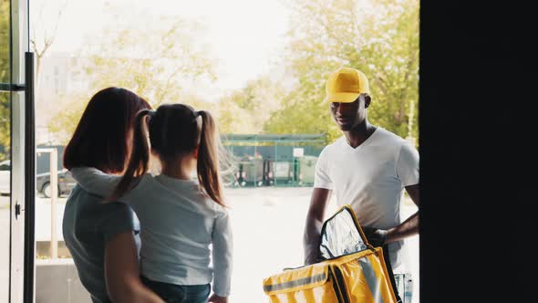 An African American Courier Brings a Little Girl a Parcel or a Gift From an