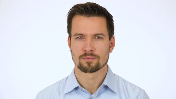 A Young Handsome Man Looks Seriously at the Camera - Closeup - White Screen Studio