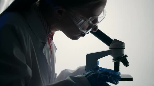 Virologist or Scientist is Looking Into Microscope alt